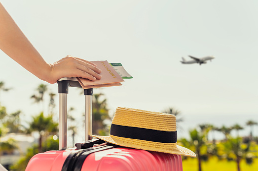 Femme s'apprêtant à partir en voyage avec sa valise rose et son chapeau